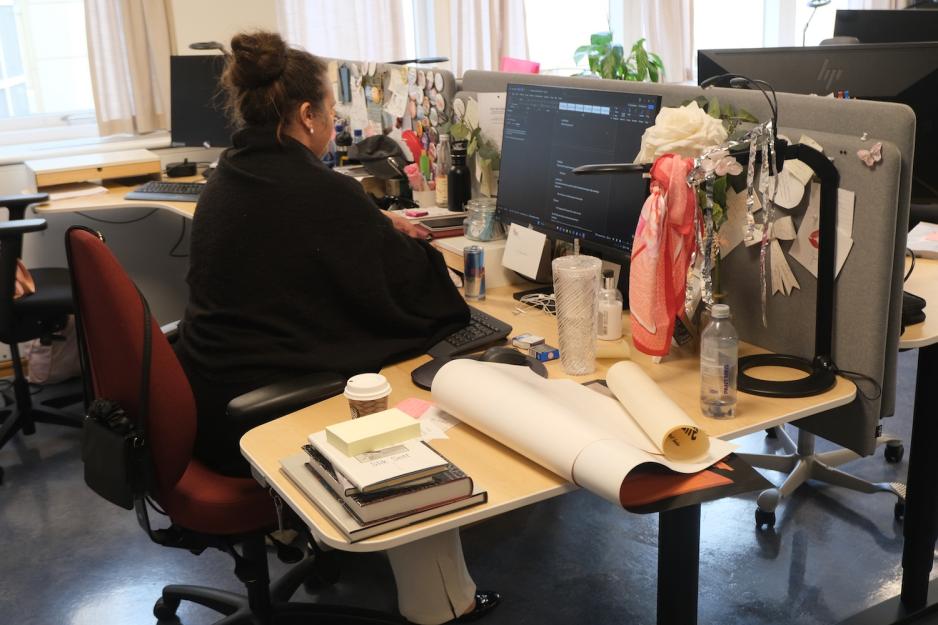 Dame sitter ved kontorpulten sin og jobber