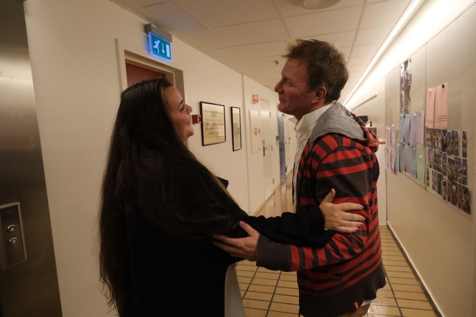 En dame og en mann hilser på hverandre utenfor en heis