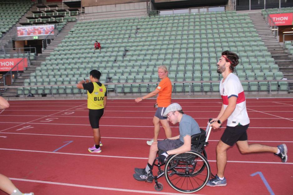 Guide som dytter rullestol på Bislett stadion