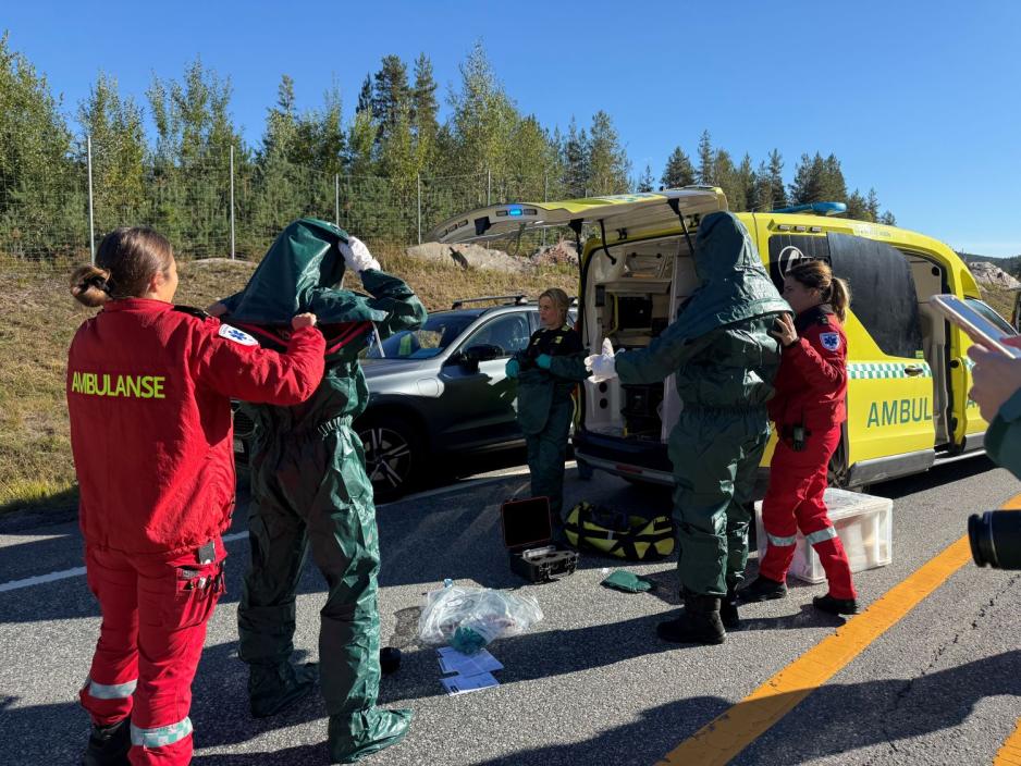 Ambulansearbeidere kler seg i beskyttelsesdrakter.