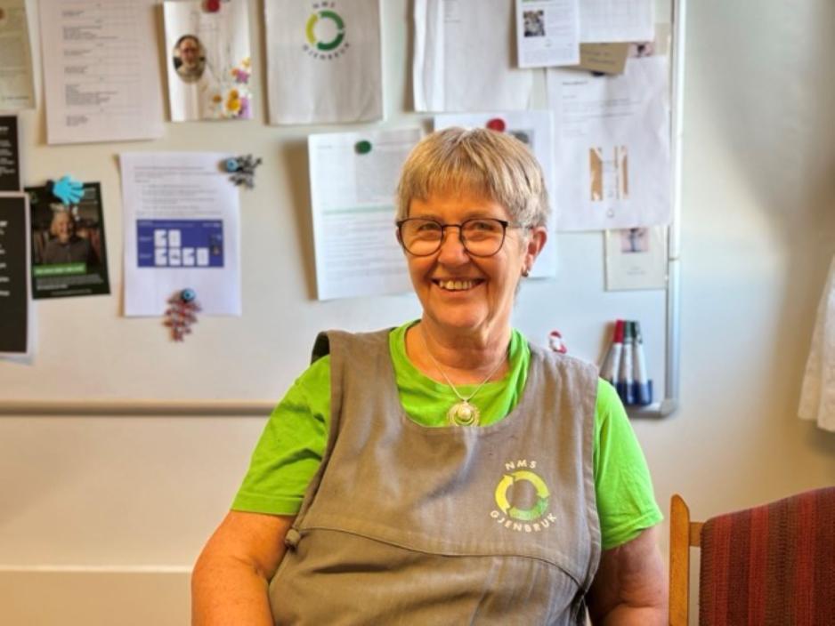 Irma Dagsloth Neef sitter p&aring; kontoret med et bredt smil og butikkens uniform.