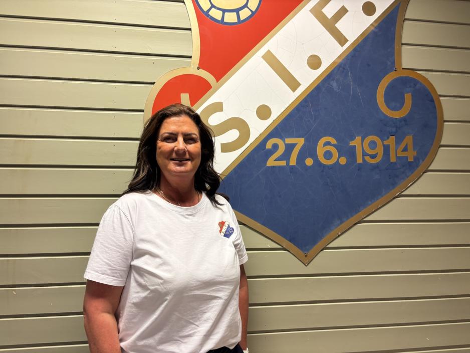 Kristin Auke Kv&aelig;rne, daglig leder i Slemmestad Idrettsforening, foran klubbens logo