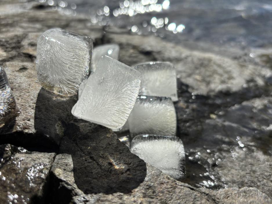Is som smelter p&aring; stein, med vann bak seg.