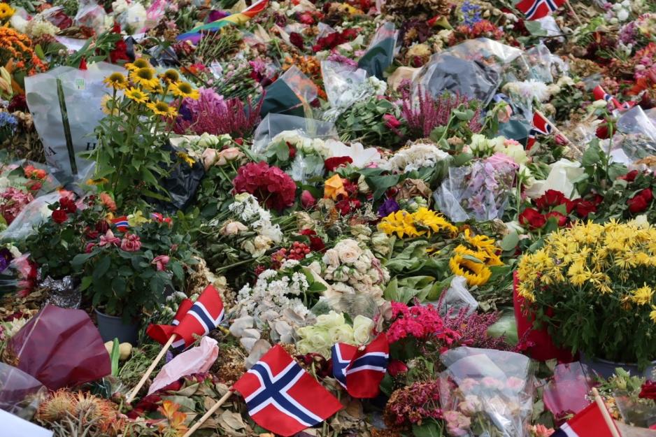 Store mengder blomster, norske flagg, tente lys og hilsener utenfor Slottet.