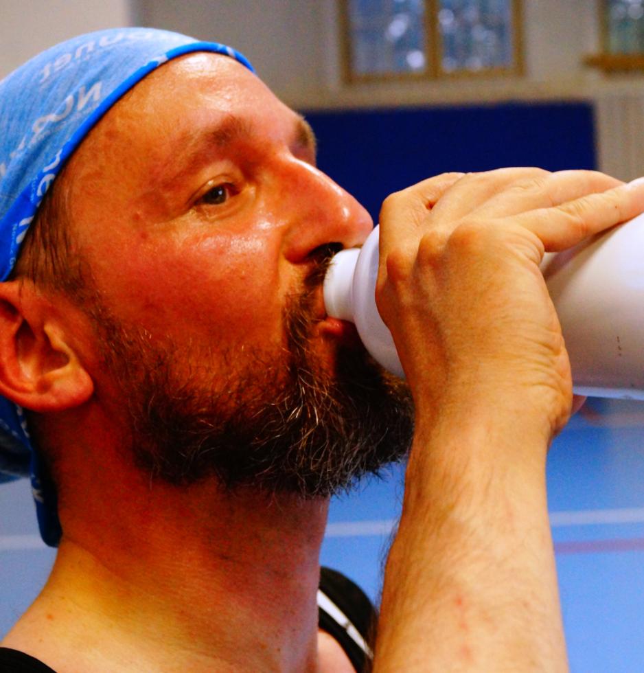En av fekterne drikker vann i gymsalen i pausen