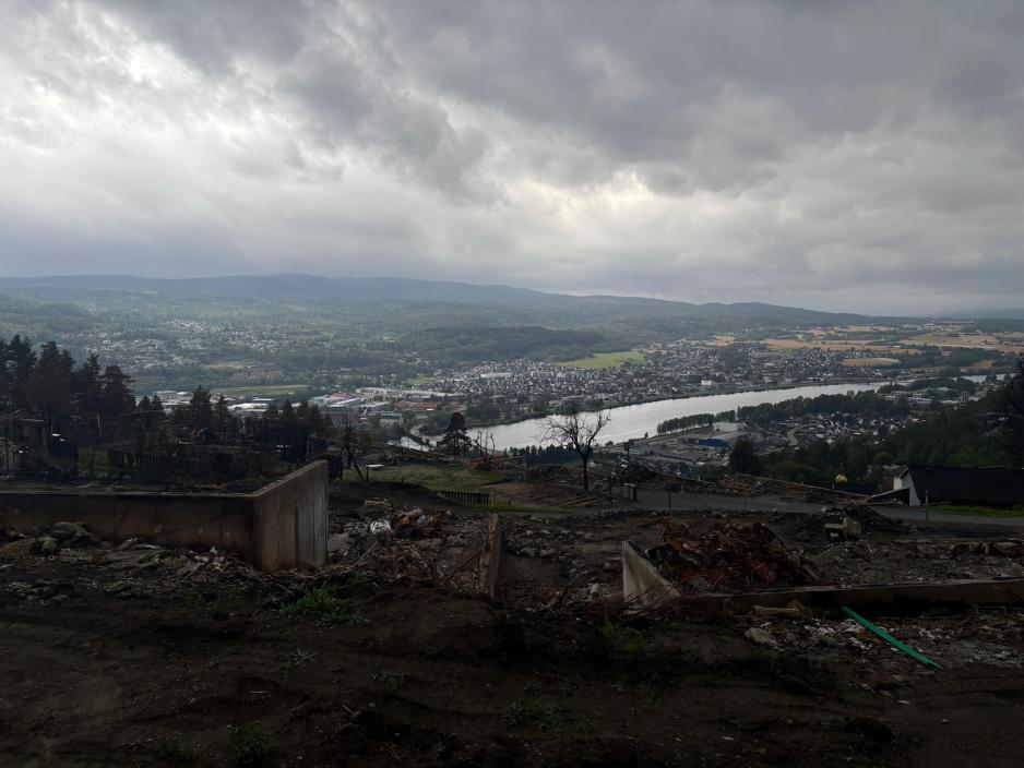 Utsikten over branntomta i Krokstadelva. I bakgrunnen ser man bygda og elven.