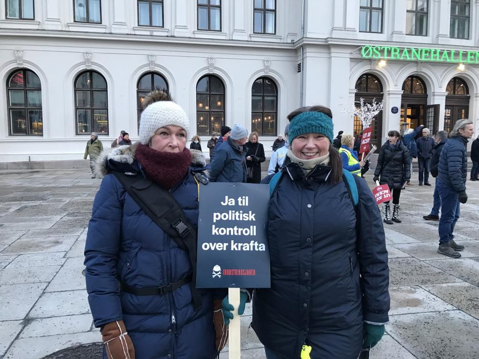 To demonstranter holder skilt utenfor Østbanehallen.