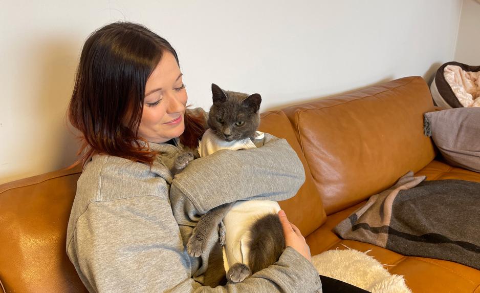 Bildet viser en frivillig ved hjelpesenteret for dyr i nød på Nordstrand med en grå katt på fanget. 