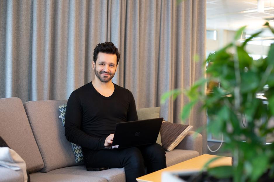 Journalisten Arash Mokhtari sitter med en computer i sofaen sin.