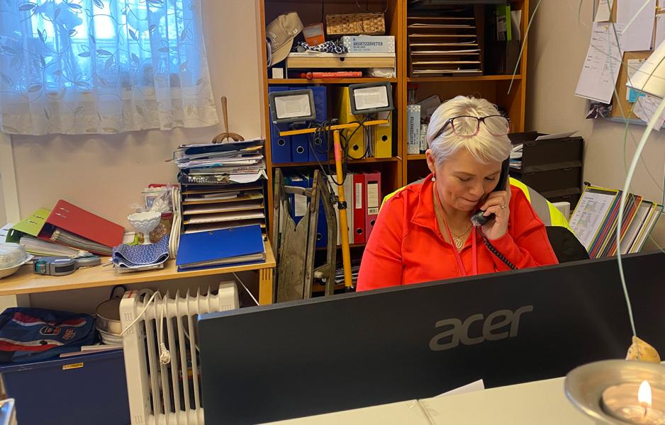 En eldre dame sitter å snakker med noen over fasttelefon.