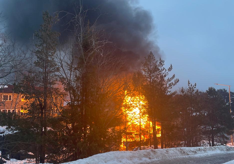 En buss brenner bak trær