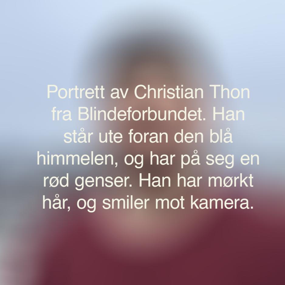En uskarp bakgrunn med den alternative teksten til bildet under. Teksten sier: Portrettbilde av Christian Thon fra Blindeforbundet. Han står ute foran den blå himmelen, og har på seg en rød genser. Han har mørkt hår, og smiler inn i kamera.