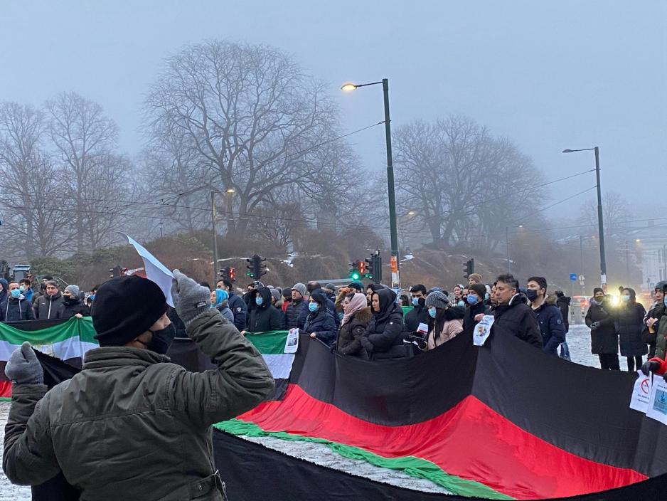 Demonstranter med plakater og afghanske flagg ved scenen.