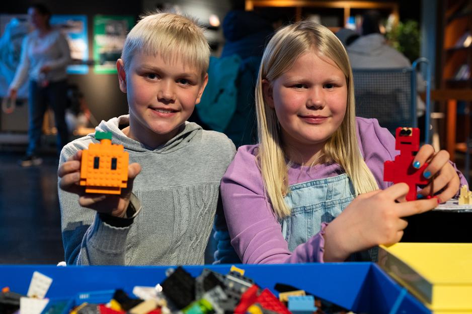 to lyshårede barn holder opp hver sin legofigur.