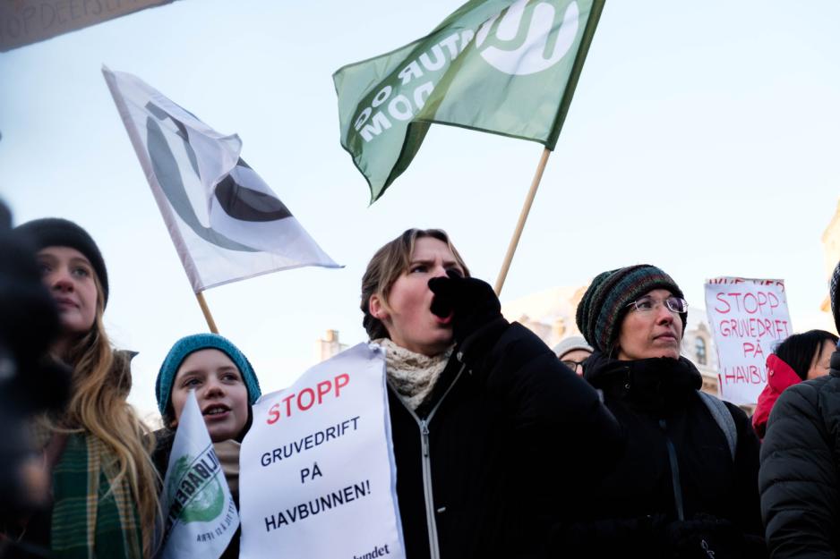 Demonstranter roper mot stortinget med flagg i bakgrunnen