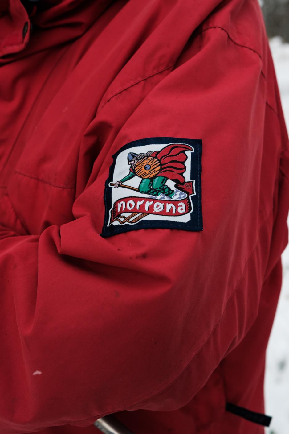 En rød Norrøna-anorakk med gammel logo