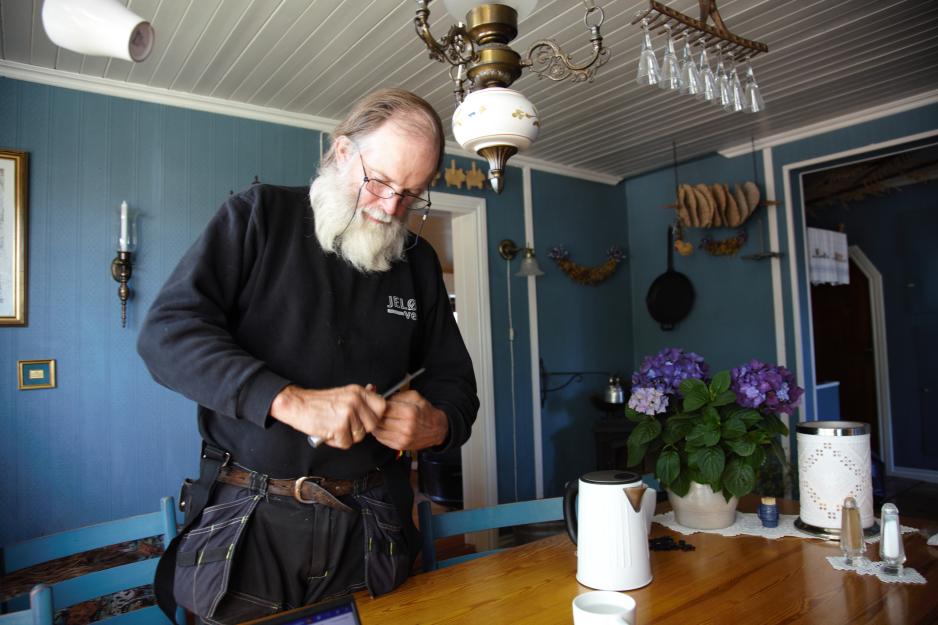 Einar Aas står og kutter opp pulverkaffeposer med en kniv