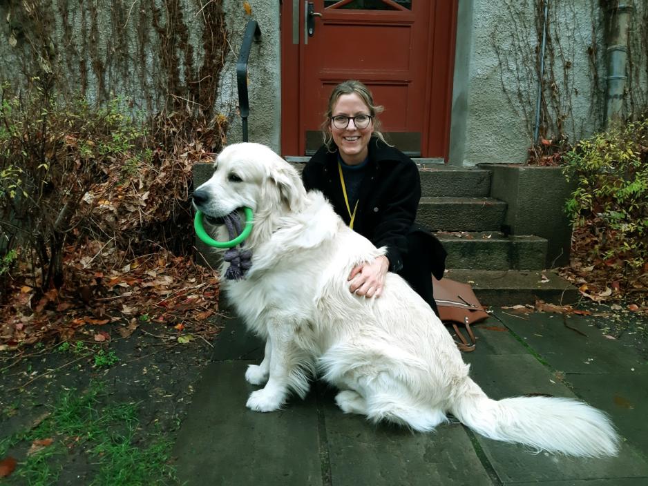 Else Werring sitter utenfor en oppgang med sin store, hvite hund