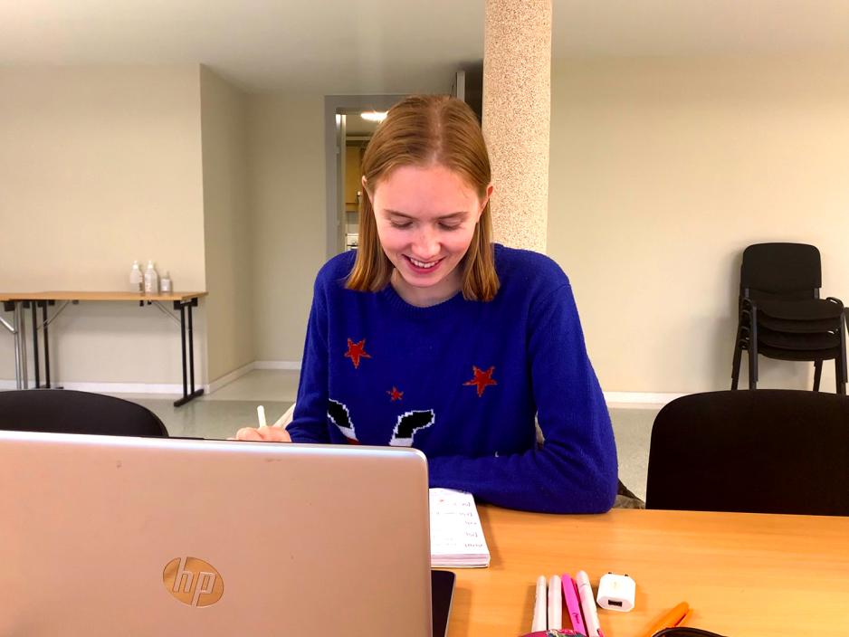 Emilie sit framfor ei datamaskin og skriv.