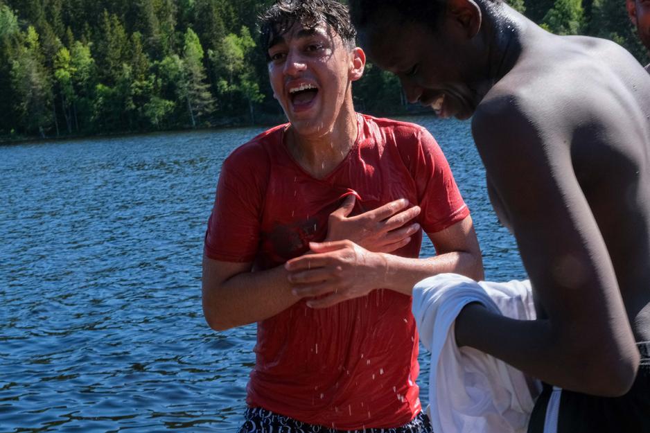 En gutt holder seg til hjertet og er helt våt etter å ha badet i sjøen.