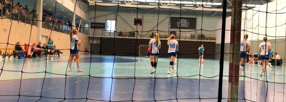 Kvinnelige håndballspillere for Nordstrand står med ryggen mot kamera nærme midten av blå bane