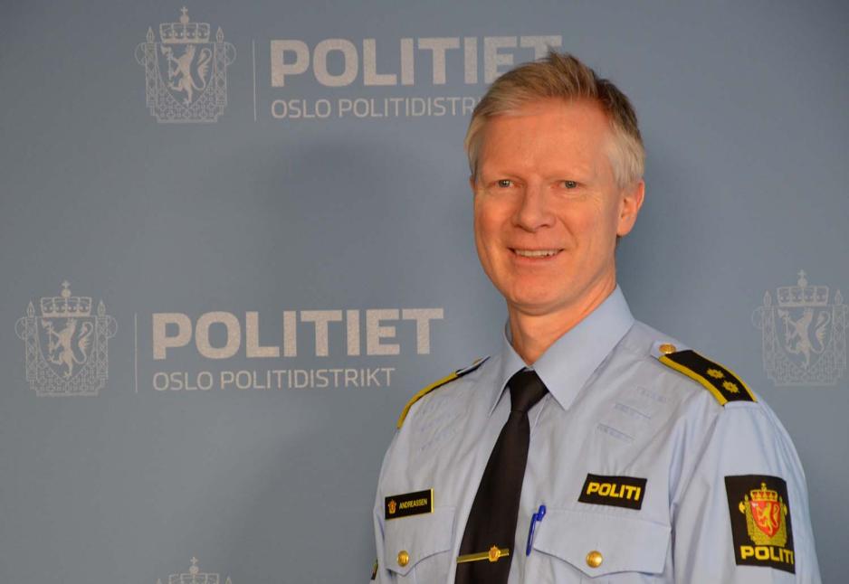 Politmann står ved en Politi plakat og smiler