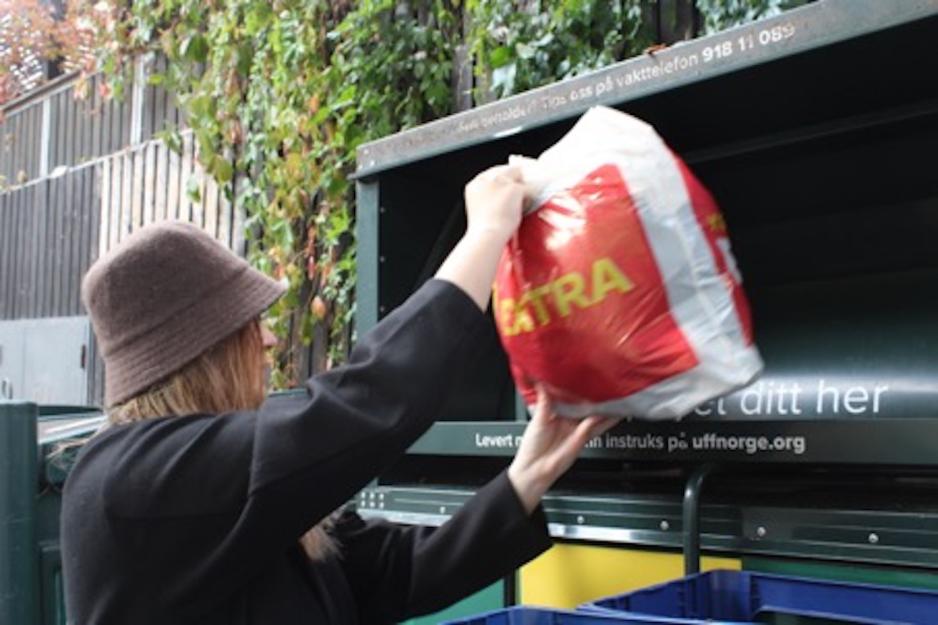 Jente som legger en plastpose med klær i en UFF-container. 