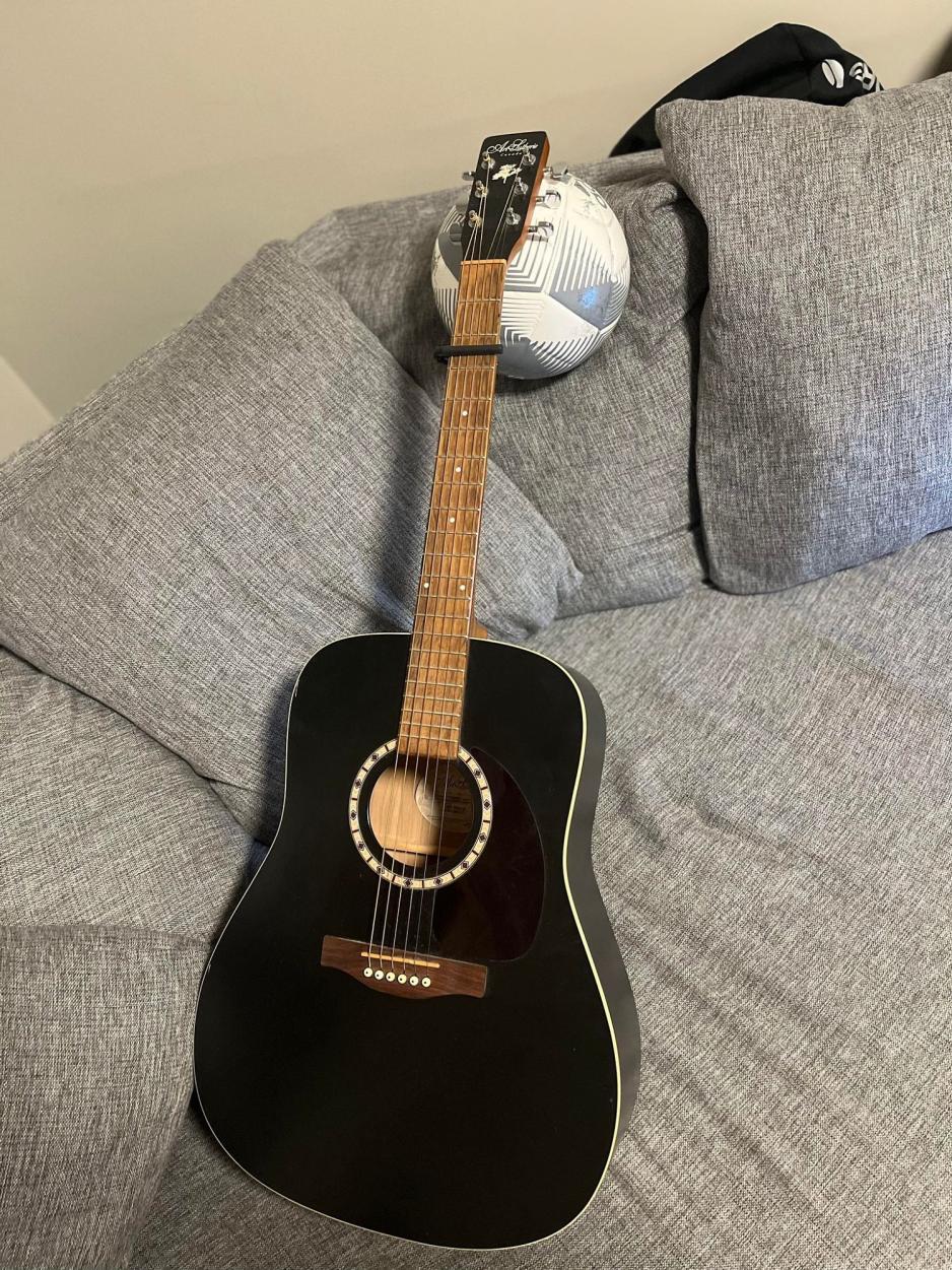 En gitar hviler på en fotball i sofaen.