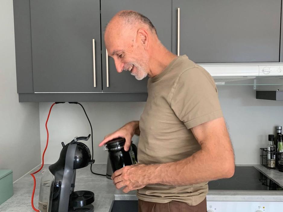 Goran Minic setter i en kaffekapsel i en kaffemaskin på kjøkkenbenken