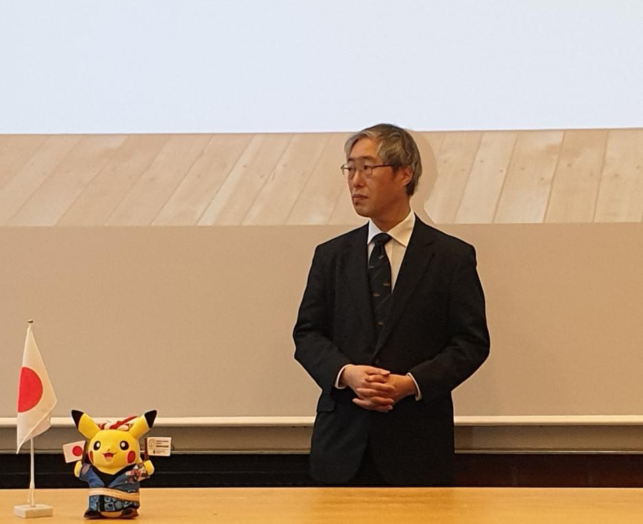 Japansk mann står ved siden av pikachu kosedyr