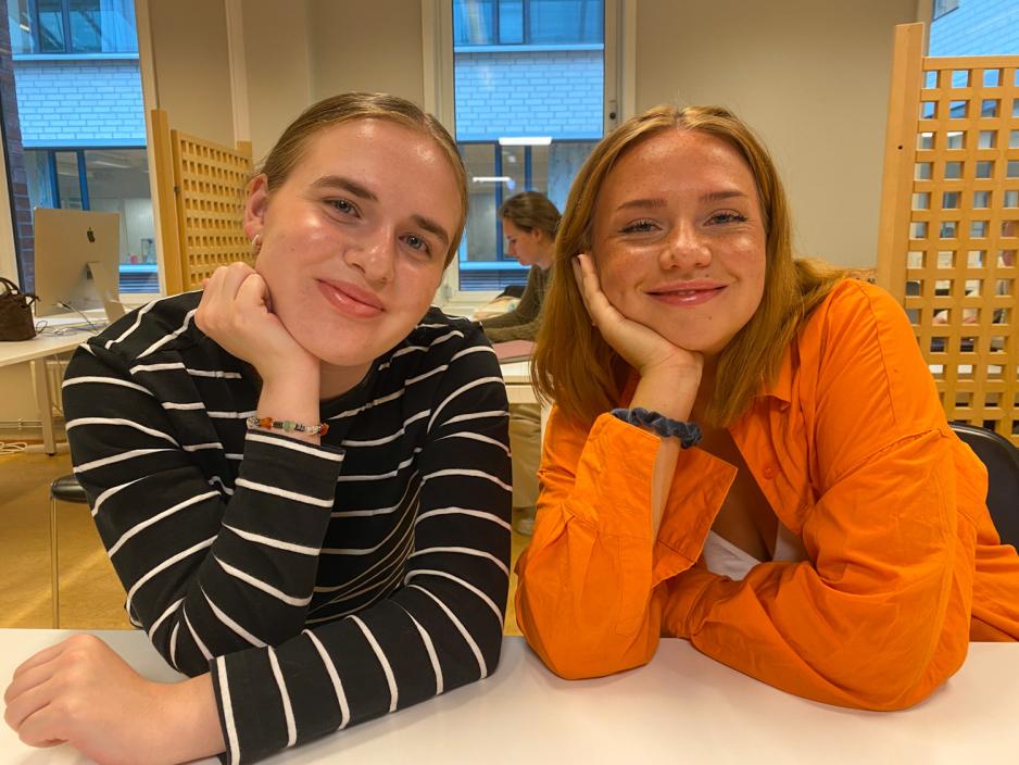to jenter smiler og ser i kameraet
