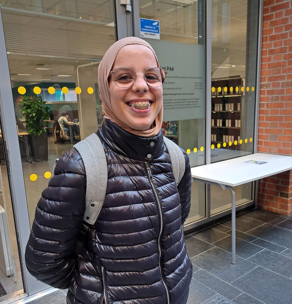 Amal Rahmati smiler med regulering utenfor biblioteket på OsloMet