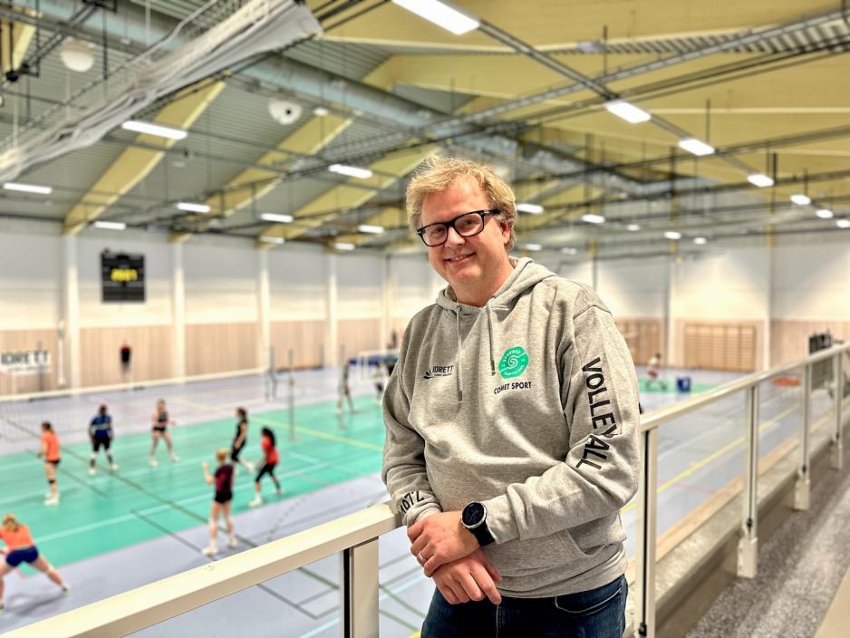 Tor Simonnæs i Stovnerhallen med mange ungdommer i bakgrunn som spiller volleyball.