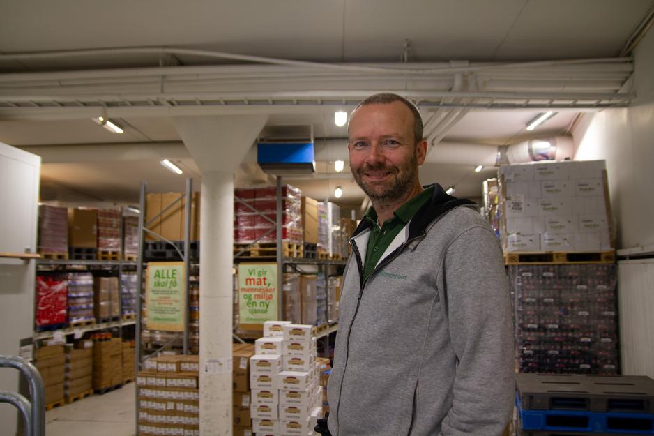 Cristiano Aubert smiler foran store hyller med mat- og drikkevarer.