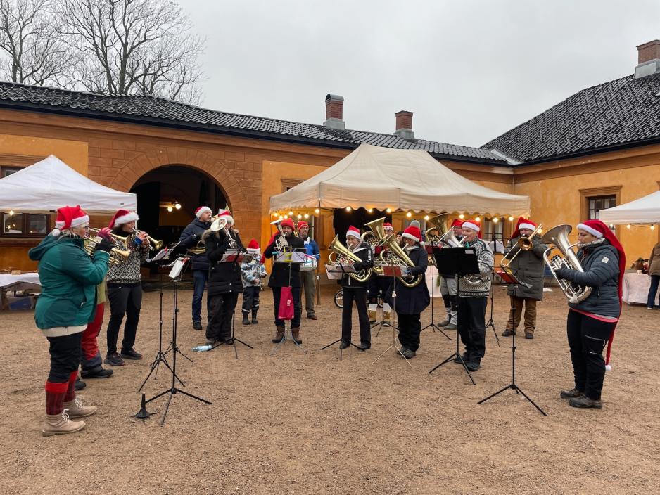 Bildet viser Sørkedalen Brass som er et brassband. 13 av bandets medlemmer er avbildet, og da bildet ble tatt spilte de julesanger. 