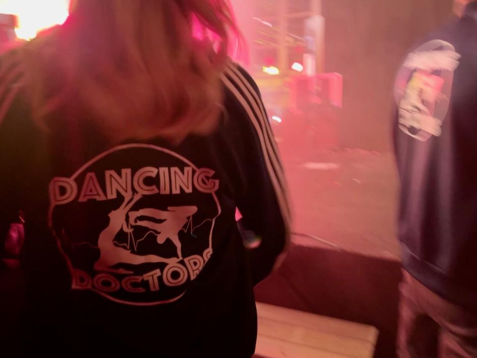 Baksiden av en jakke, hvor det står "Dancing Doctors". 