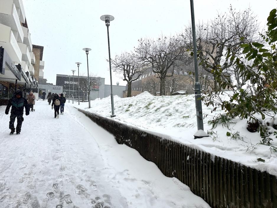 Folk som går ned bakken dekket av snø. 