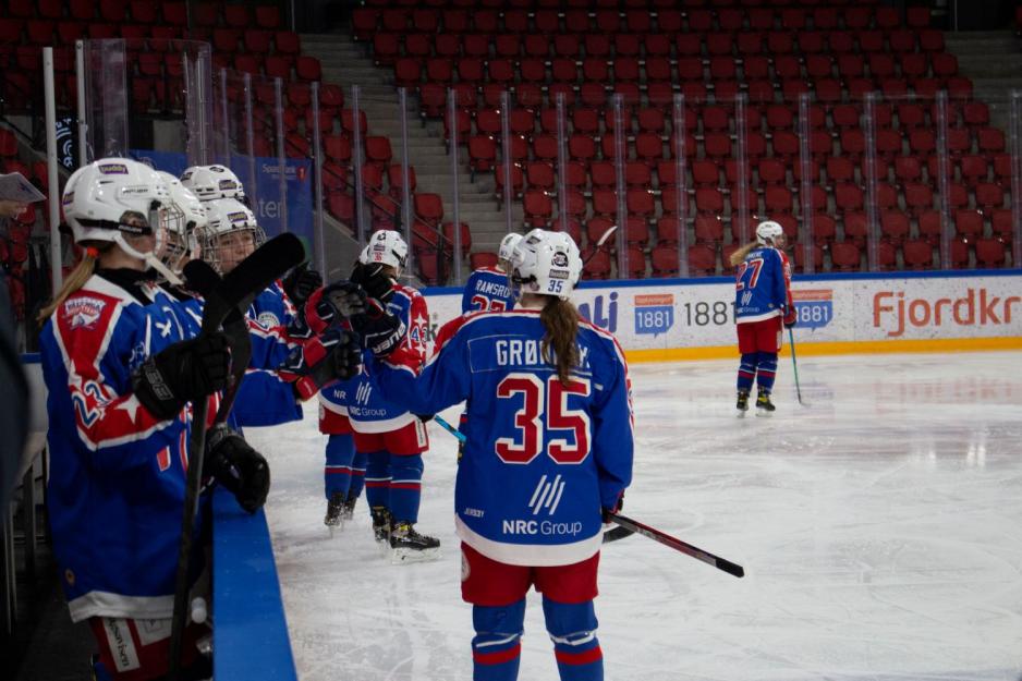 Ishockeyspillere damer feirer et mål.