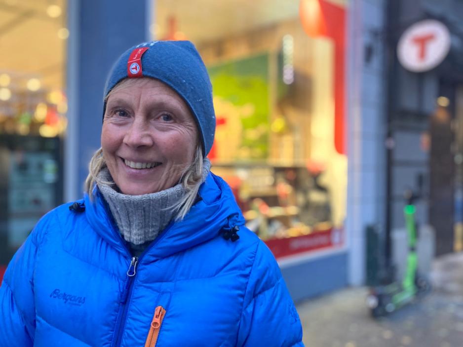 Janet Bydal står i turklær foran en DNT-butikk ved Karl Johan i Oslo. Hun smiler og det har skumret ute. 