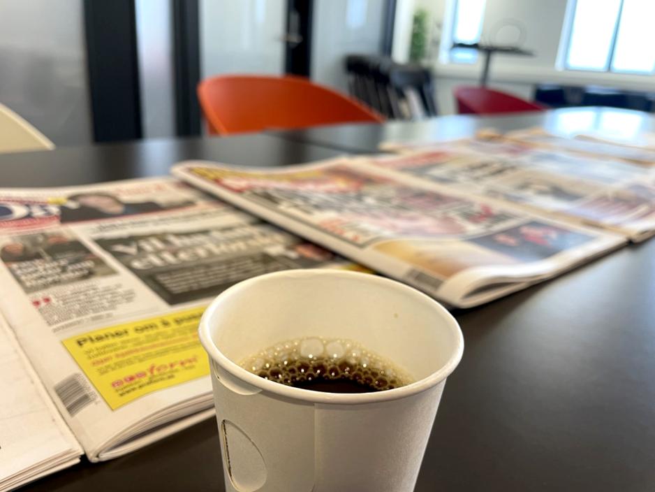 en kopp kaffe foran dagens aviser på bordet