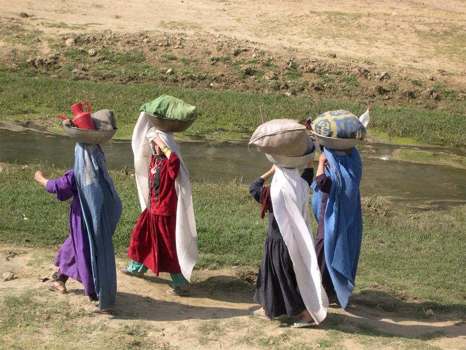 Kvinner bærer sekker med klesvask ved Kabul-elven