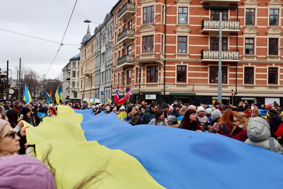 Mange som holder et langt banner av det ukrainske flagget mellom seg.