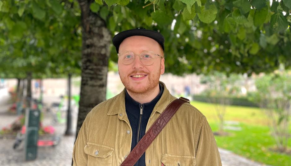 Et foto av smilende Lars Gøran Hansen under et tre på Karl Johans gate i Oslo. 