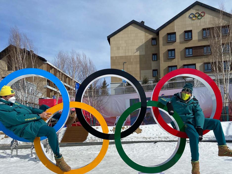 To gutter som poserer med en skulptur av de olympiske ringene. 