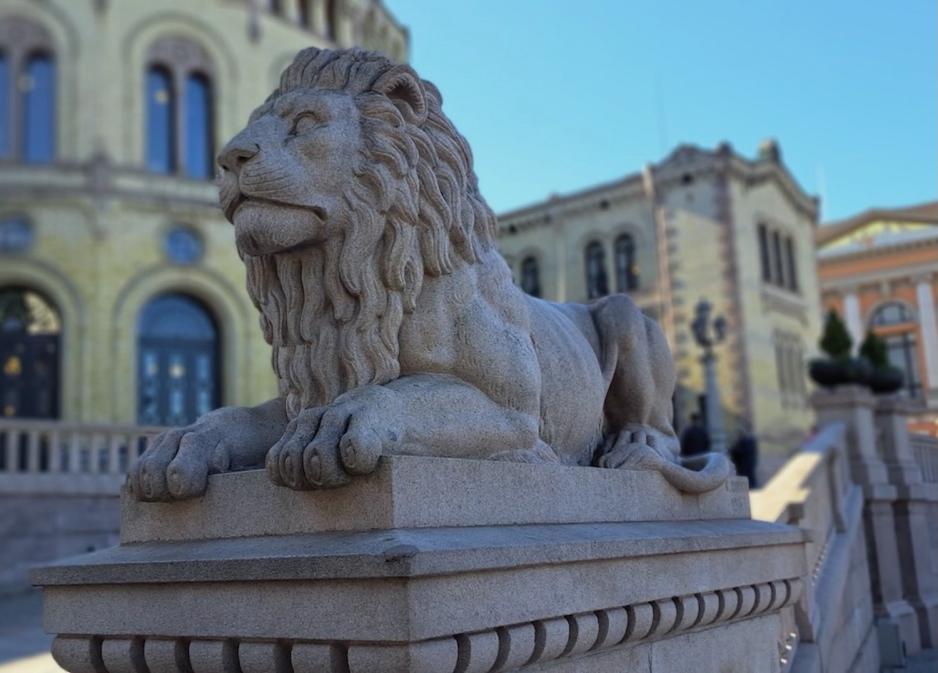 Granittskulptur av løve på Løvebakken med Stortinget i bakgrunnen.