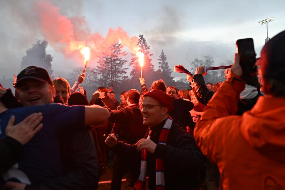 Fotballsupportere omringer en fotballspiller i feiring.