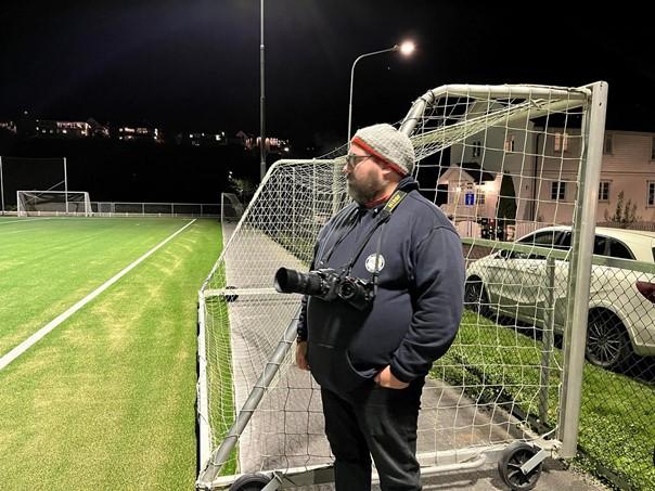 Marius Helgå står på sidelinjen og forbereder seg på å ta bilder av kampen.