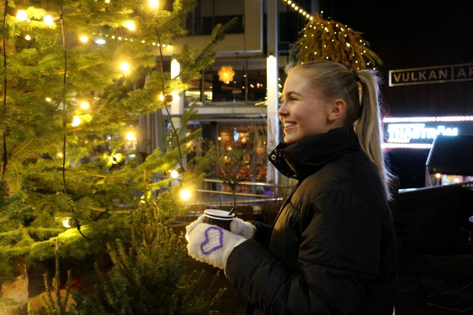 Jente står ved juletre og drikker gløgg