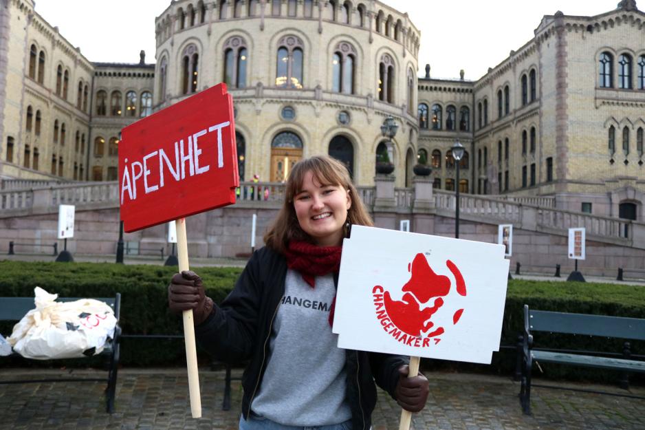 Mathilda Angeltveit nestleder i Changemaker Norge holder to plakater foran Stortinget