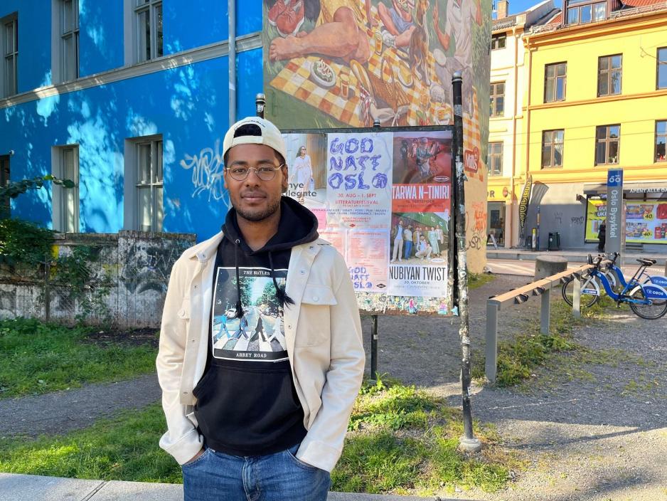 Matias Tunold smiler til kamera, foran plakater for en filmfestival på Grünerløkka.